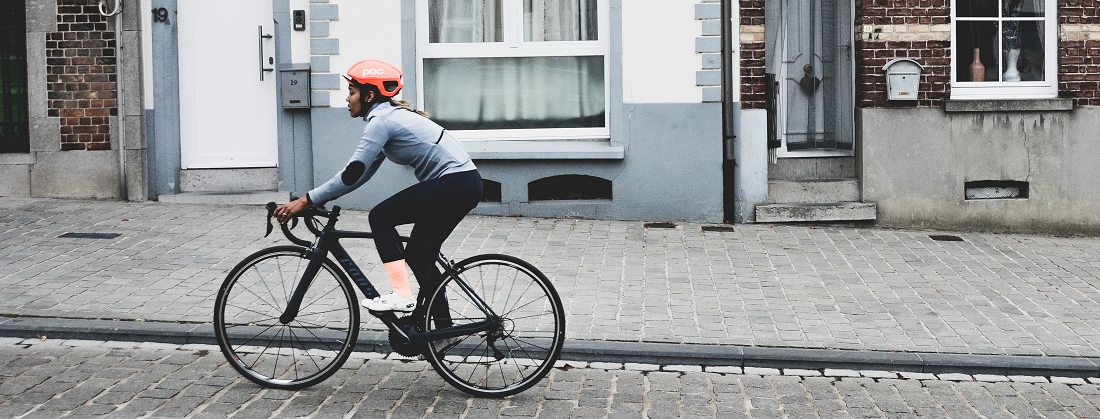 Woman cycling on a cobbled street by Coen Van de Broek from Unsplash 