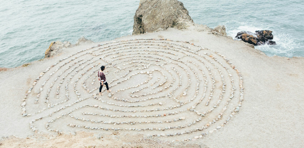 person walking a meditation labyrinth on beach during daytime