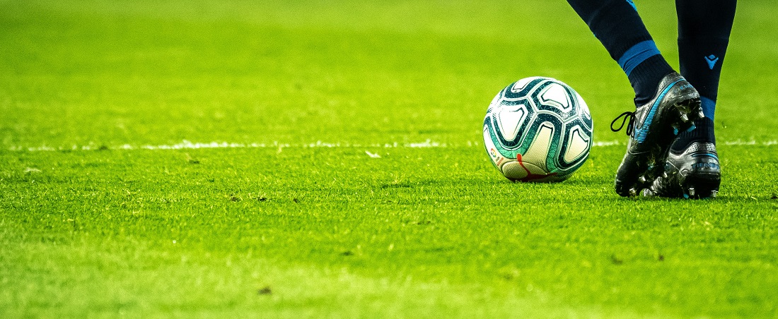 Soccer player kicking a ball on a green pitch