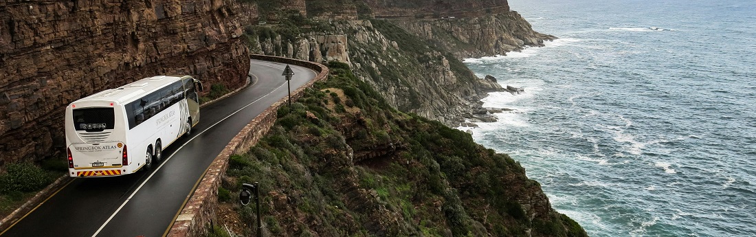 White bus on a road near a cliff by Mads Thomsen