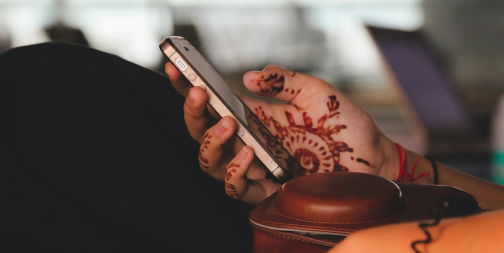 woman using mobile phone with henna on hands