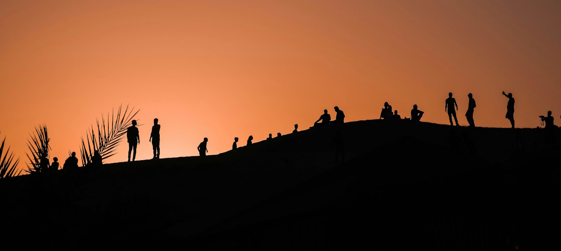 Sillhouettes of a group of people in the desert at sunset