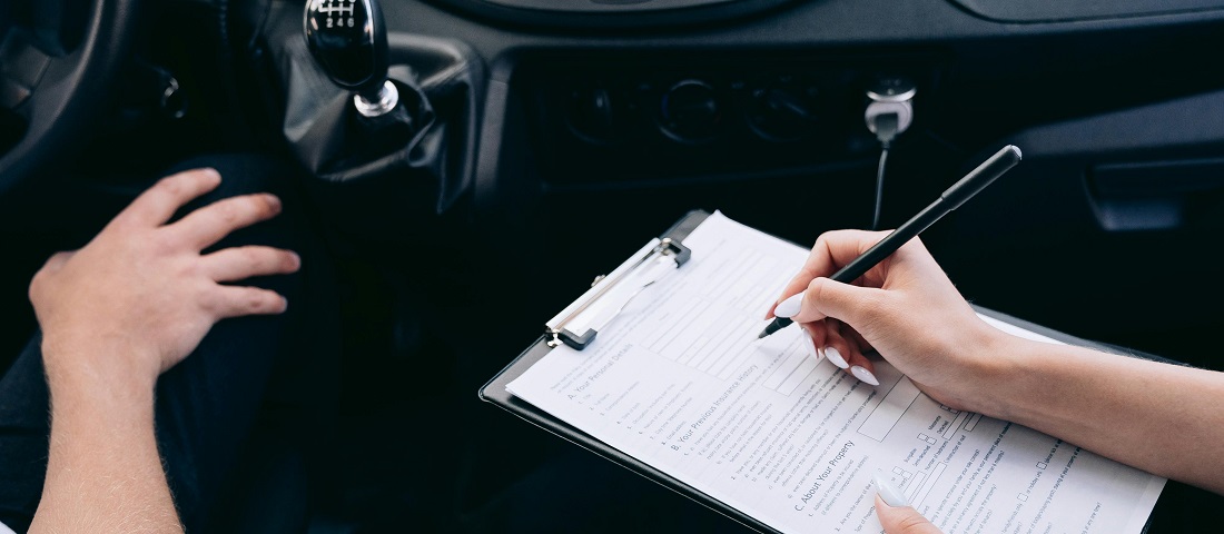 Person writing on a clipboard inside a car by Mikhail Nilov