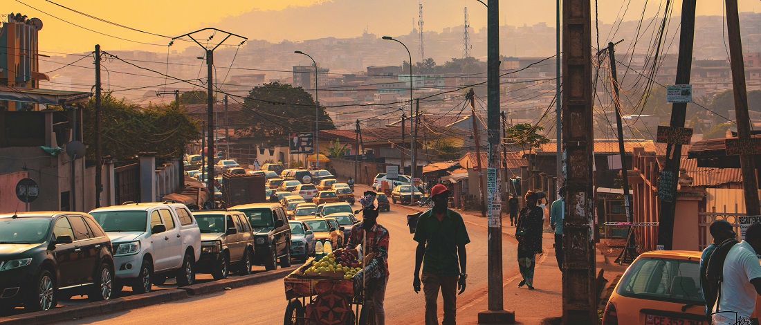 A busy street with cars and people by Japazon Fonkwo