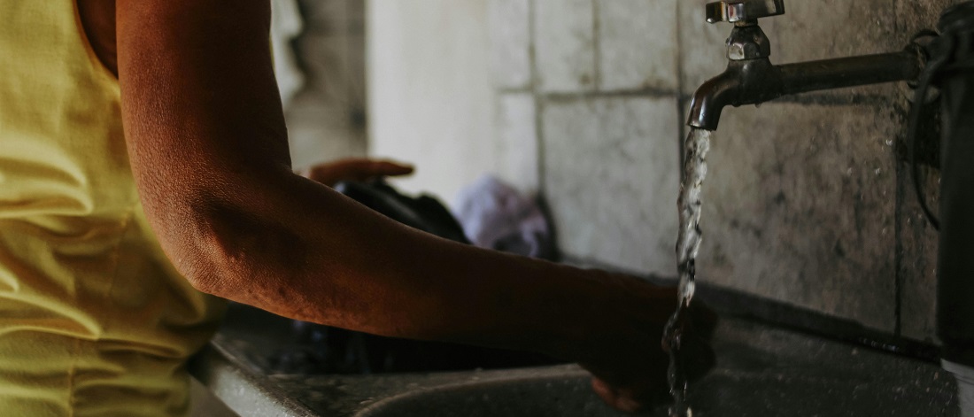 Person washing their hands under a running tap by Gabriel Frank