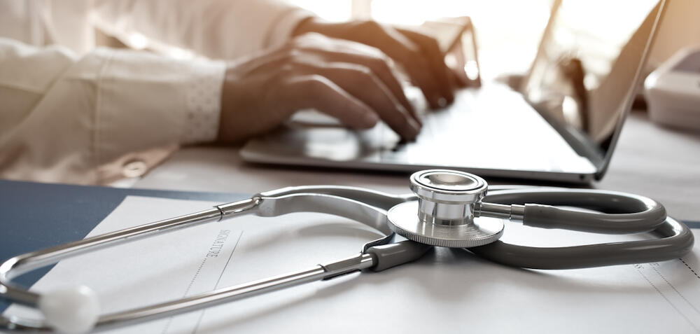 Doctor using a laptop with a stethoscope on the table