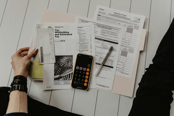 Person holding paper near pen and calculator